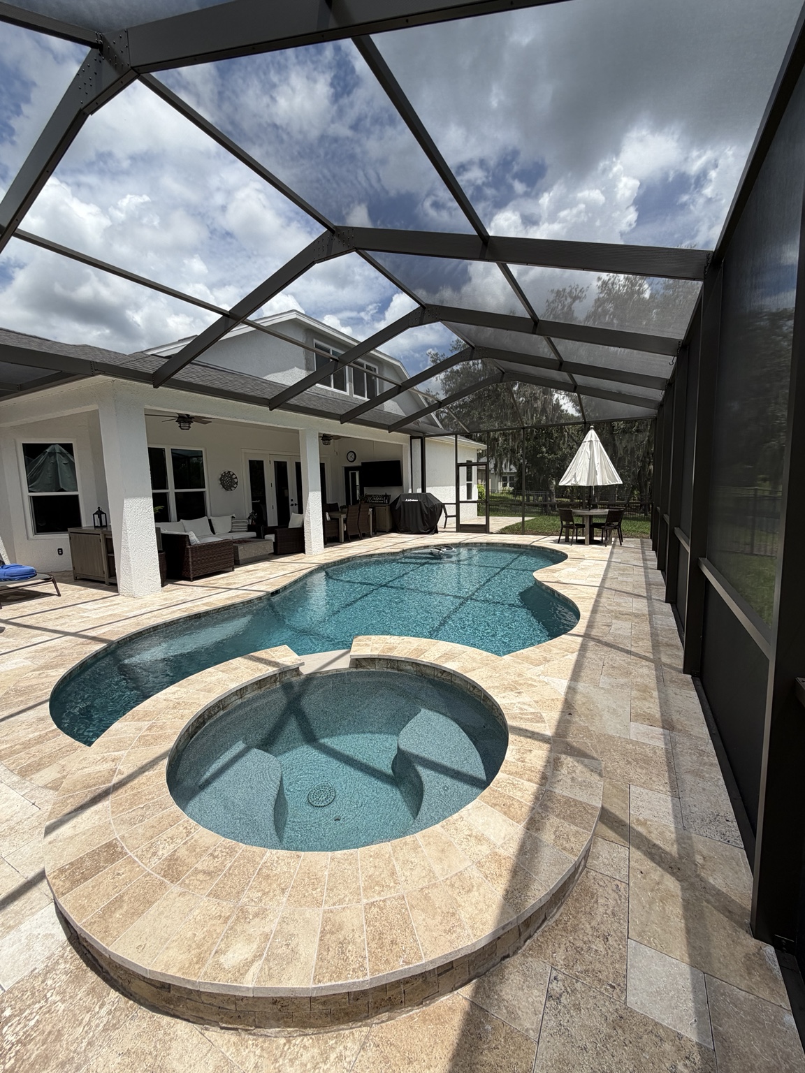 Pool and spa inside a dark-framed screen enclosure